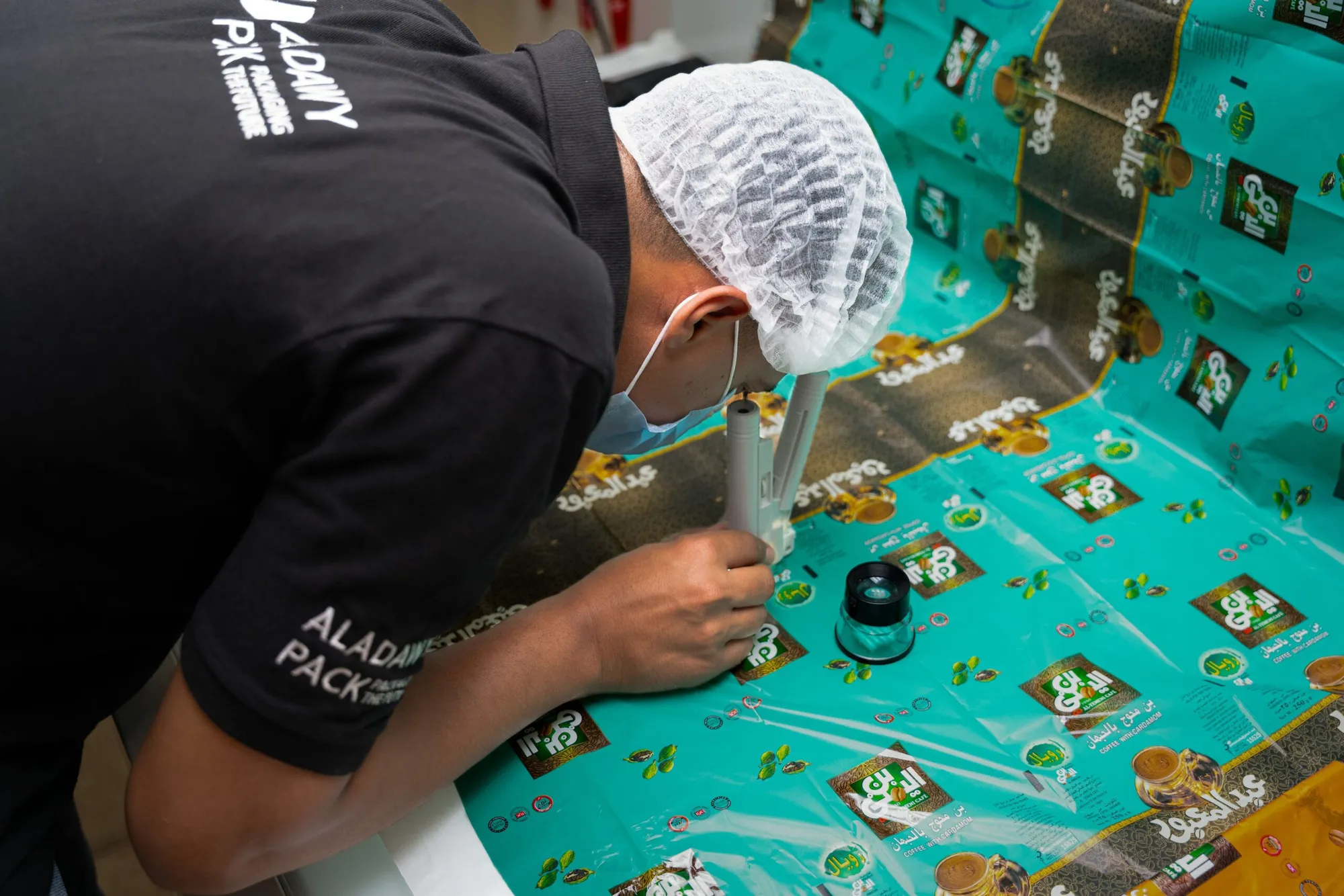 A technician examining printed film through a magnifier on the inspection table