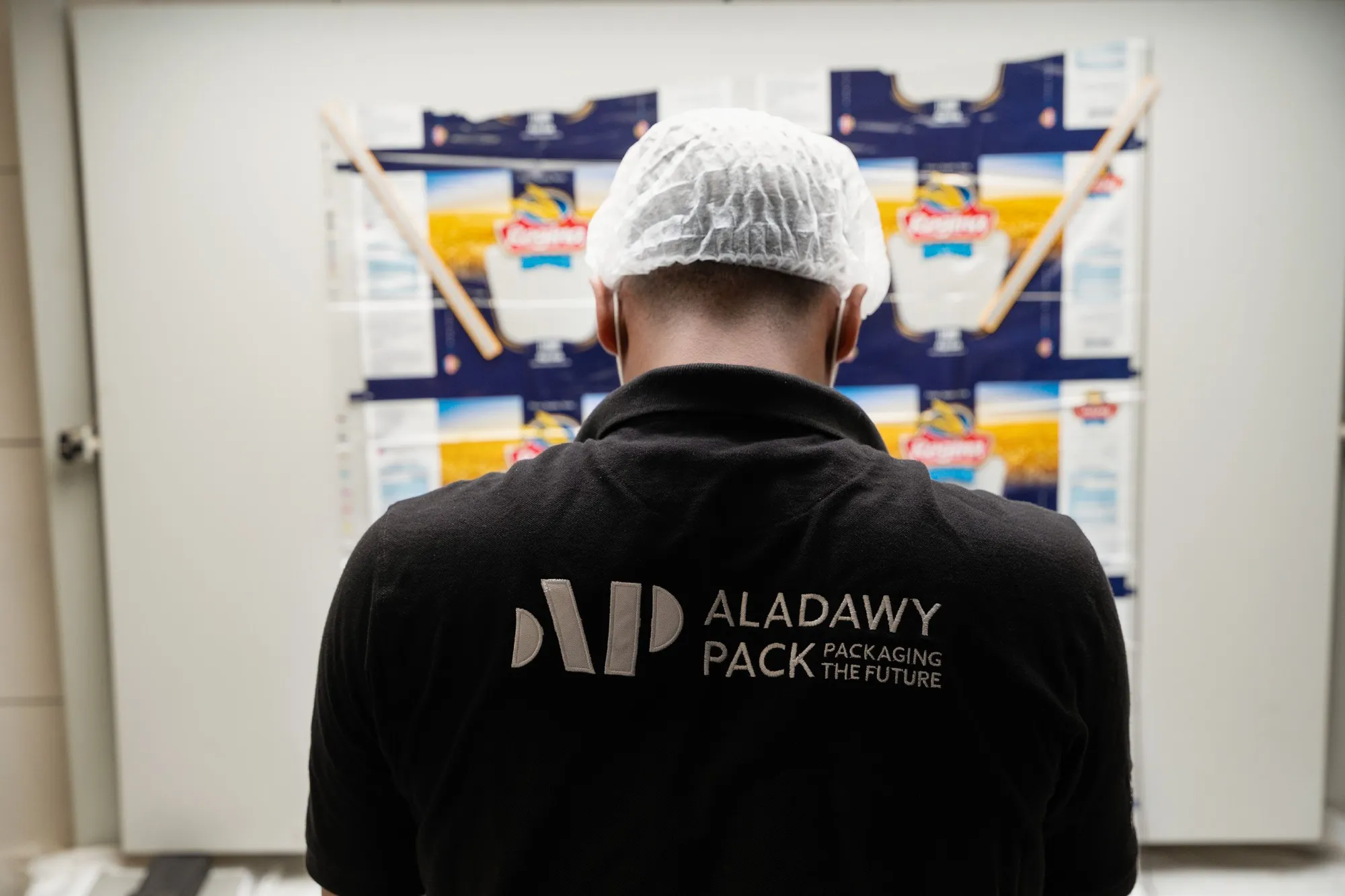 An Aladawy Pack technician reviewing a rack of finished printed cartons