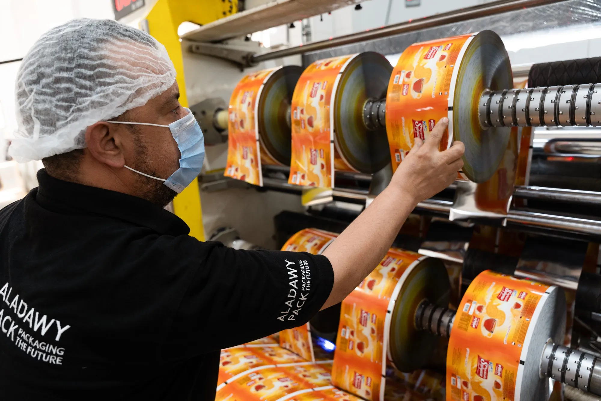 An operator loading printed film reels onto the slitter shaft
